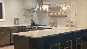 Eine moderne Küche mit einer zentralen Kochinsel, Barhocker, einer Kaffeemaschine und einem Toaster.
