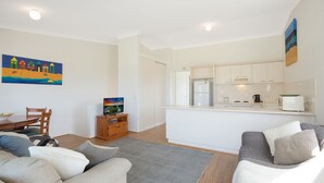 Um espaço compacto com área de refeições, cozinha compacta e sofá.