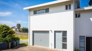 Um edifício moderno de dois andares com uma porta de garagem, uma antena parabólica e uma pequena janela.