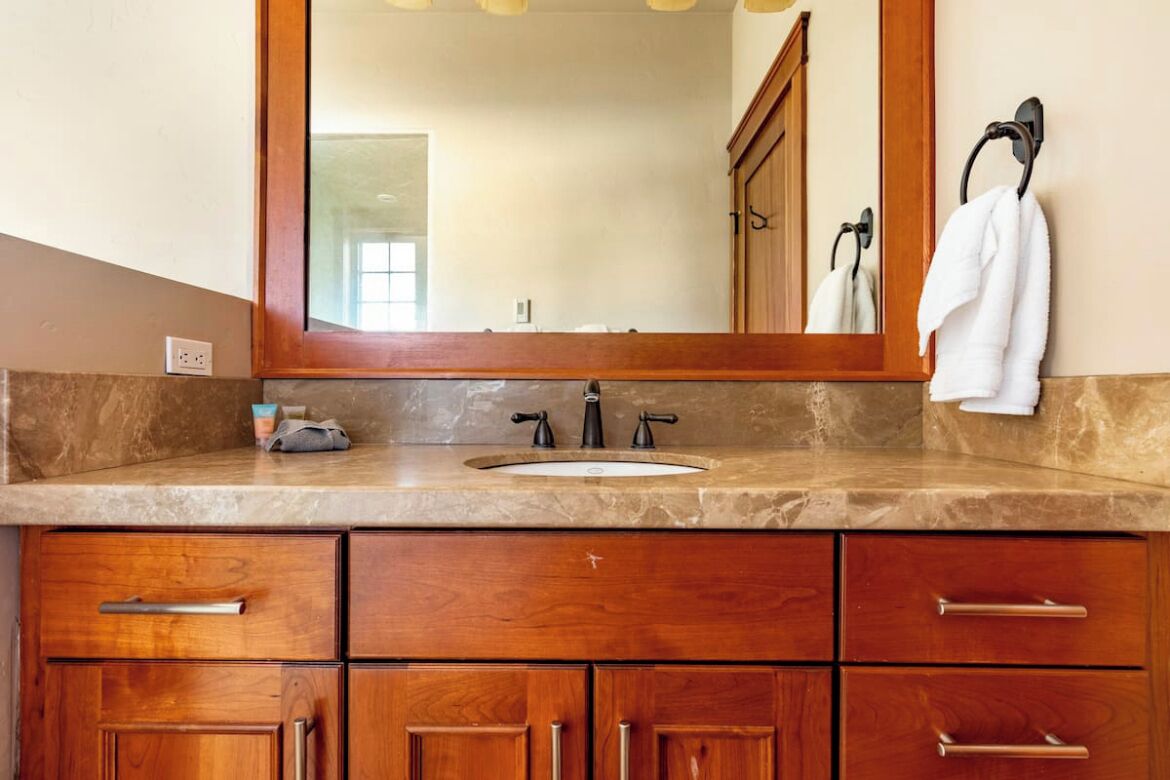 Une salle de bain avec un grand miroir, un lavabo et des meubles en bois.