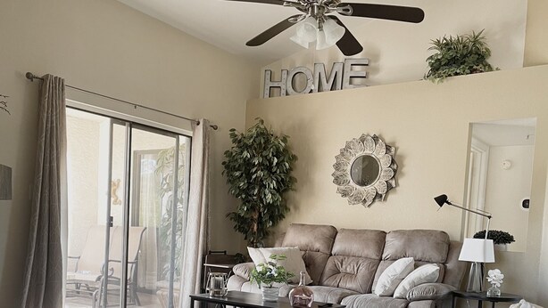 A living room with a ceiling fan, a sofa, a coffee table, and a large potted plant. - Your Scottsdale Getaway awaits you with this wonderful poolside condo ! (Scottsdale)