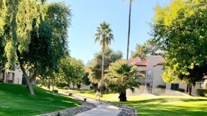 A paved pathway with a stone border, surrounded by well-maintained grass and trees. - Your Scottsdale Getaway awaits you with this wonderful poolside condo ! (Scottsdale)