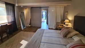Ein Schlafzimmer mit Bett, Schreibtisch, Stuhl und Blick ins Freie.