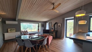 Ein moderner Essbereich mit Holzboden, einem zentralen Tisch mit Stühlen und Blick durch große Fenster.