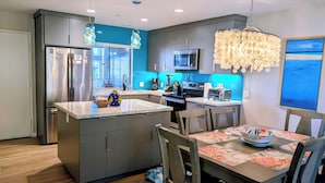 A modern kitchen with a central island, stainless steel appliances, and a dining area with a table set for four.