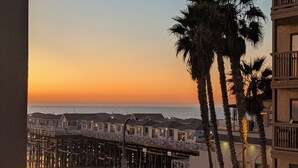 A beachfront hotel with a pier, palm trees, and outdoor seating.