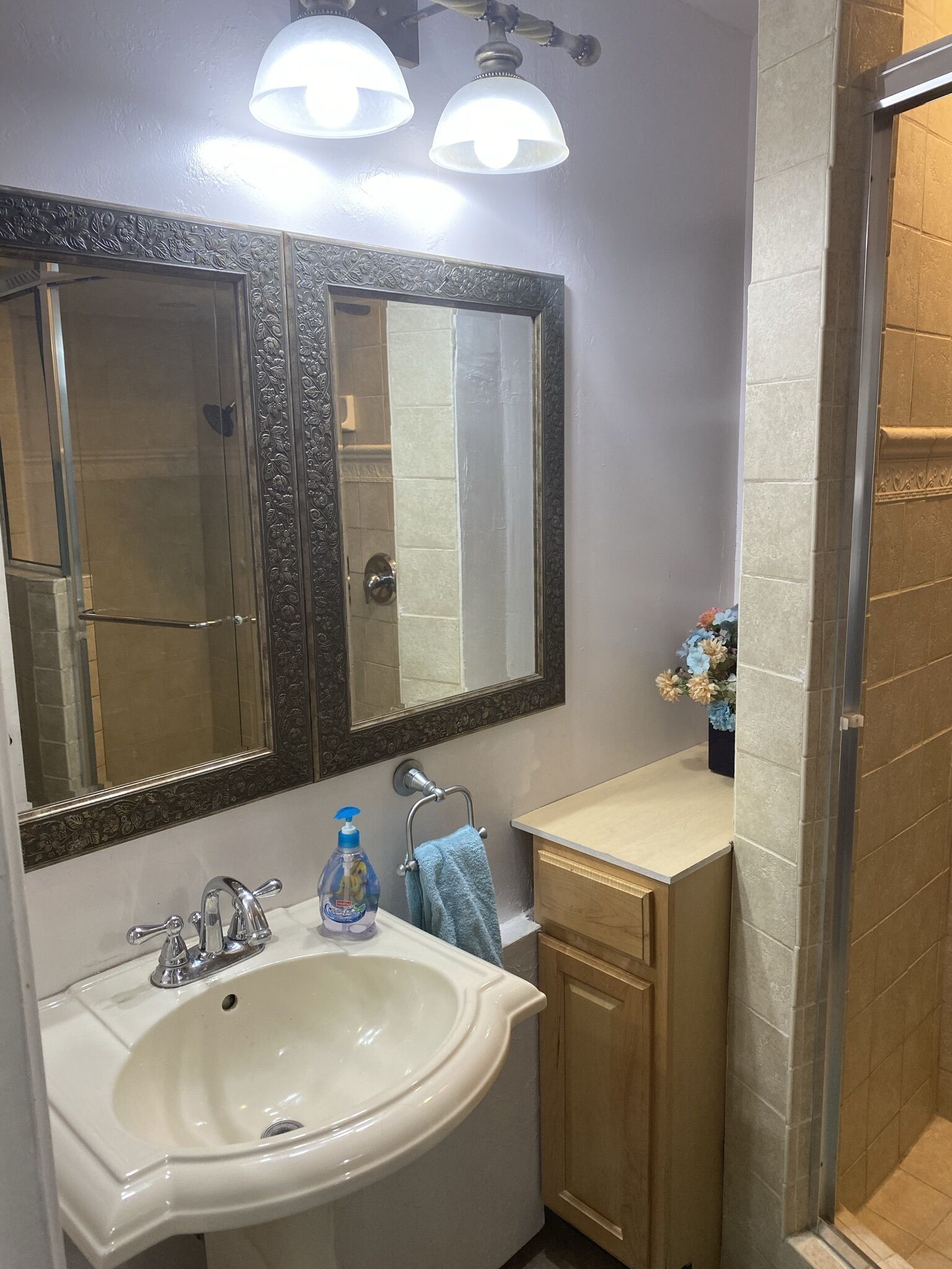 A bathroom with a large mirror, a sink, a towel rack, and a shower area.