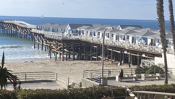 A pier extending into the ocean with beachside accommodations.