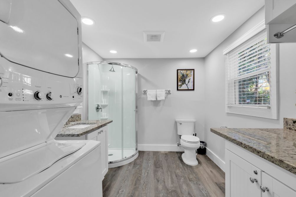 A modern bathroom with a glass shower enclosure, a toilet, and a granite countertop.