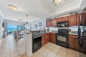 A modern kitchen with wooden cabinets, a black stove, and a refrigerator.