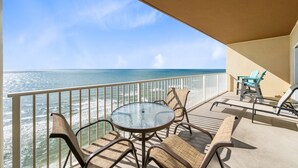 A balcony with a round table and chairs, overlooking a beach and ocean. - Crystal Shores West 1002- Look No Further This is Where You Need to Be! Reserve (Gulf Shores)