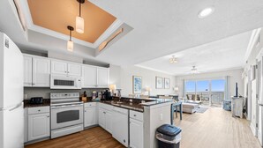 A spacious kitchen with white cabinets, a central island, and a ceiling with recessed lighting. - Crystal Shores West 1002- Look No Further This is Where You Need to Be! Reserve (Gulf Shores)