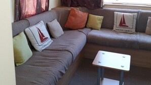 Una sala de estar moderna con un sofá gris, una mesita blanca y cojines decorativos.