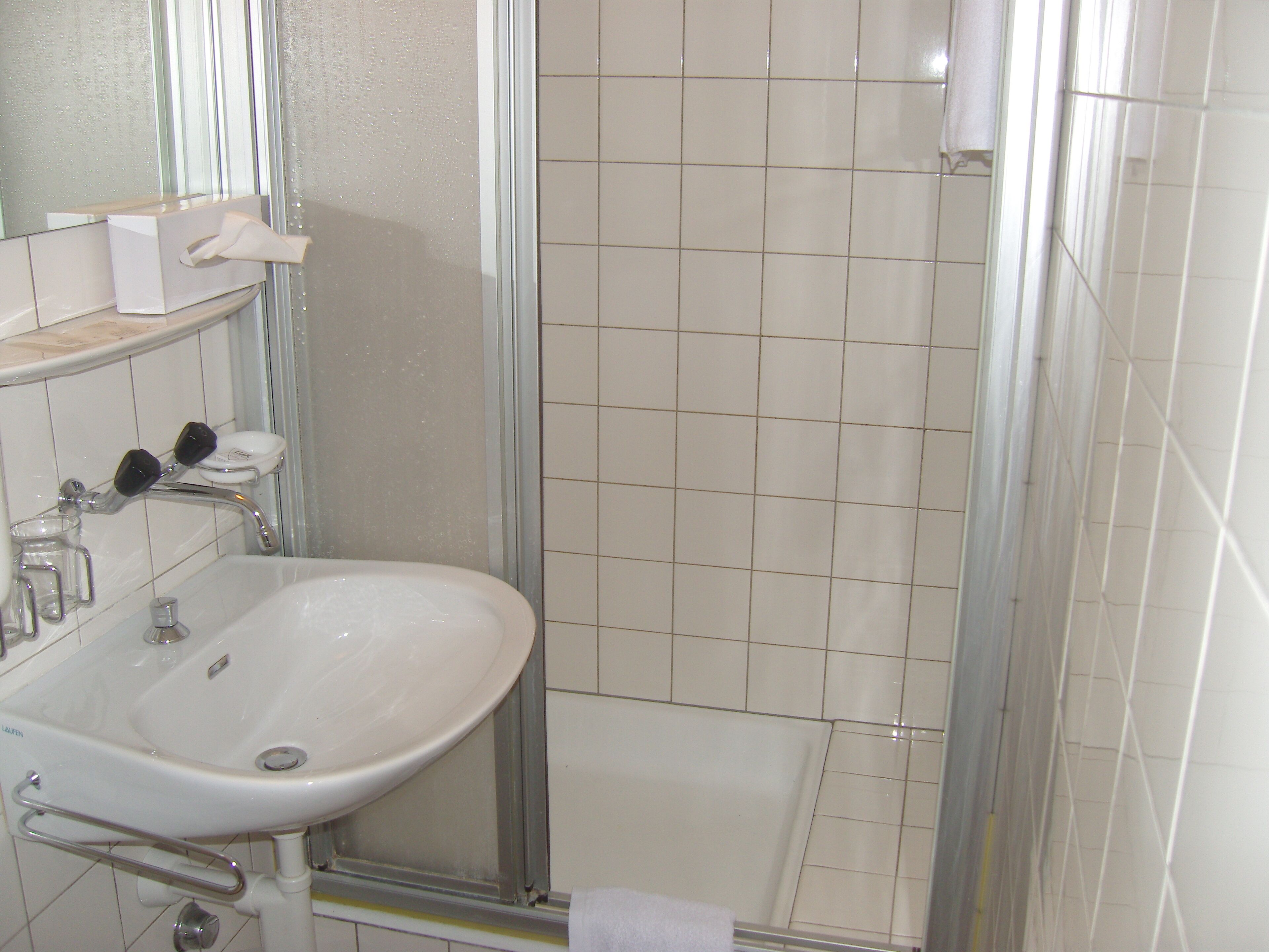 A bathroom with a white sink, mirror, and tiled walls.