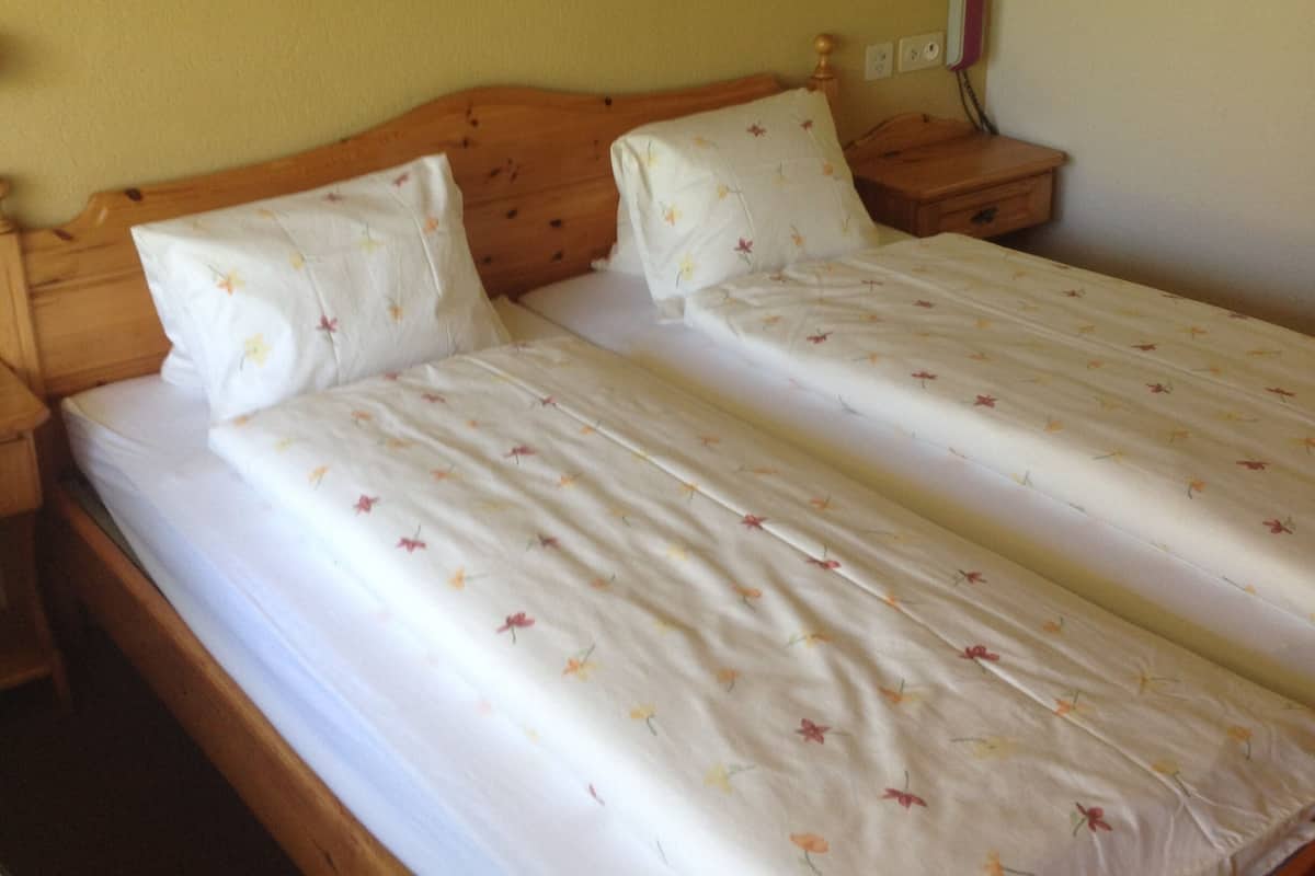 A double bed with floral bedding, wooden headboard, bedside tables, and a wall-mounted telephone.