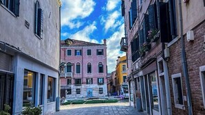 Une rue étroite, bordée de bâtiments des deux côtés, un ciel dégagé et un sol pavé.