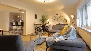 A modern living room with a sofa, coffee table, and a dining area with chairs.