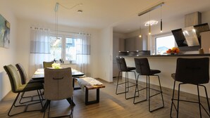 A modern kitchen with a dining area, wooden flooring, and contemporary bar stools.