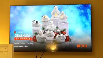 A television displaying a Christmas-themed Netflix series advertisement with a snowy scene and cupcakes.