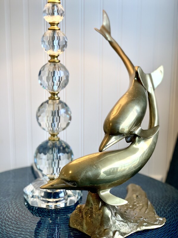 A decorative metal sculpture of two dolphins on a textured blue surface.