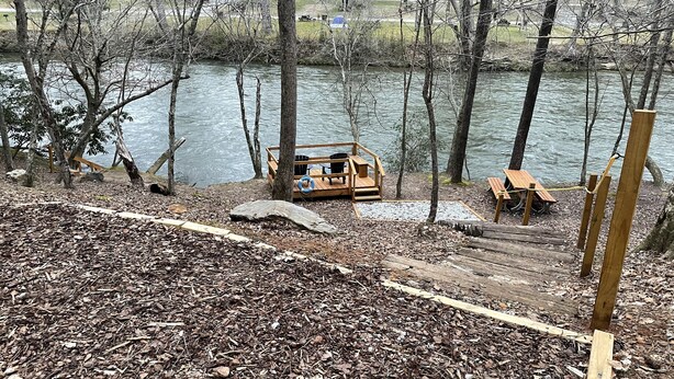 A wooden deck with a bench and a picnic table by a river. - Riverside Cabin with Gameroom, Hot Tub, Fishing (Ellijay)
