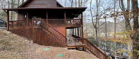 A cabin with a balcony, a chimney, and a deck with outdoor seating.