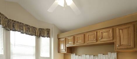 A bedroom with a large bed, wooden headboard, two bedside lamps, and a ceiling fan.