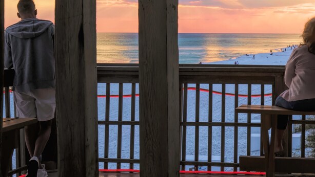 Une terrasse en bois avec une balustrade donnant sur une plage.