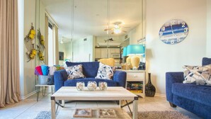 Un salon avec un canapé bleu, une table basse en bois et une horloge au mur.