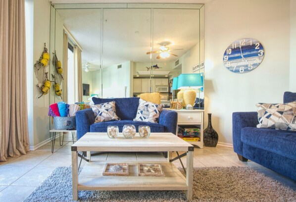 Un salon avec un canapé bleu, une table basse en bois et une horloge au mur.