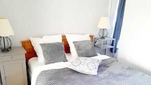 Een netjes ingerichte slaapkamer met een bed, twee nachtkastjes en een bedbank.