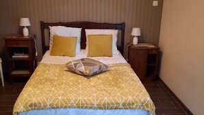 Cama bem arrumada com colcha de padrão geométrico, duas mesas de cabeceira com abajures e cabeceira de madeira.