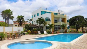 Un hôtel doté d’une piscine, d’un espace extérieur aménagé et de palmiers.