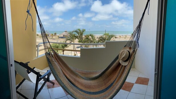 Un hamac sur un balcon avec vue sur la plage et les palmiers.