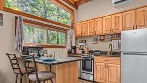 Una cocina con armarios de madera, una isla central con taburetes de bar, un refrigerador y una estufa.