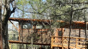 Una cabaña rústica con terraza de madera y chimenea de piedra.