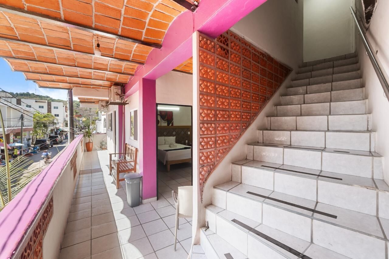 A residential building with a balcony, a staircase, and a room with a bed.