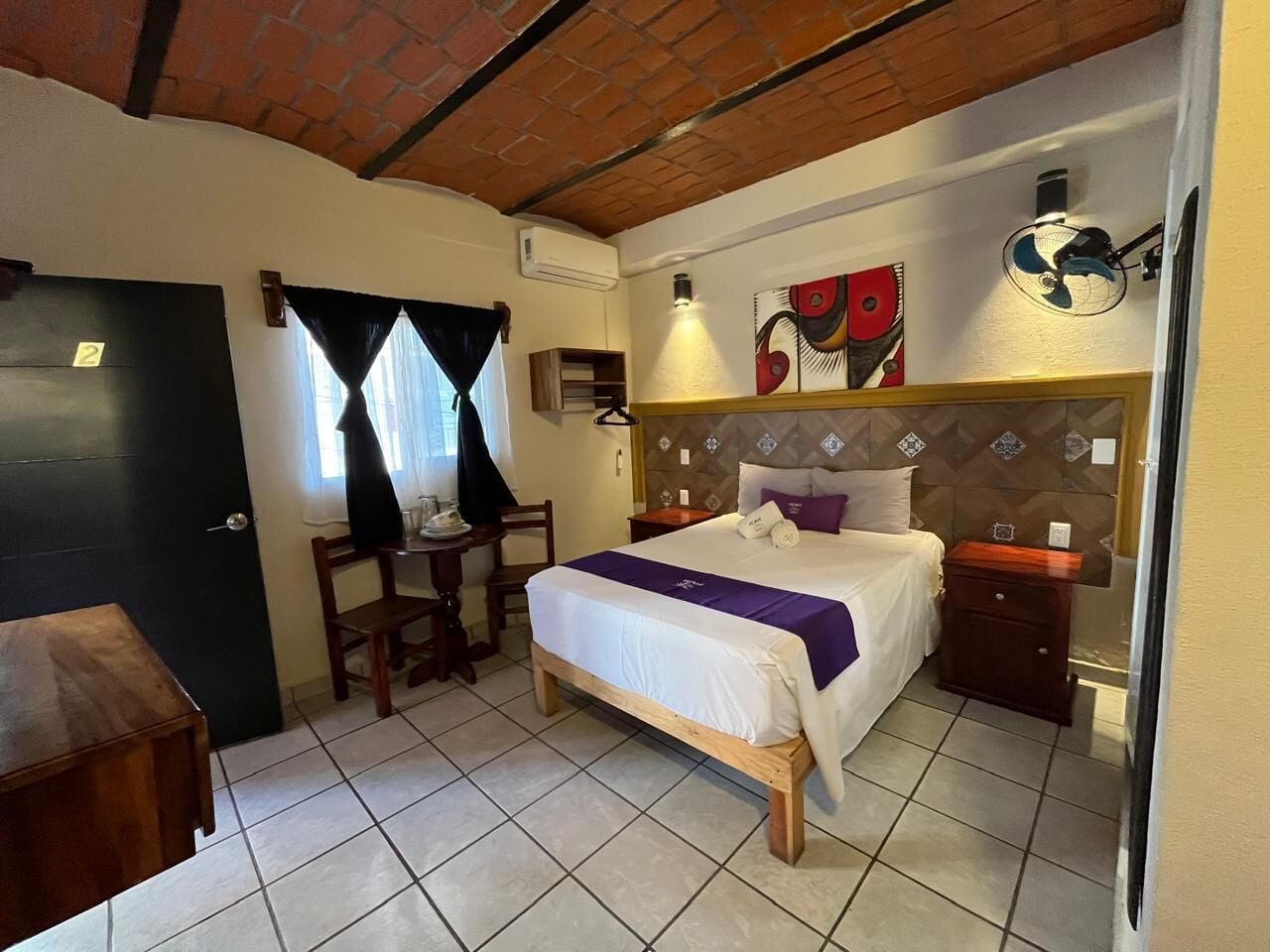 A bedroom with a bed, bedside table, chair, and a small desk with a chair.