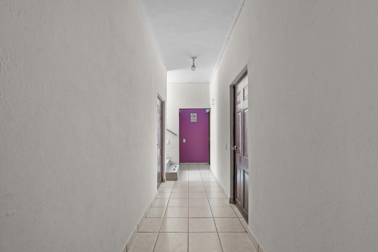 A hallway with white walls and a purple door at the end.