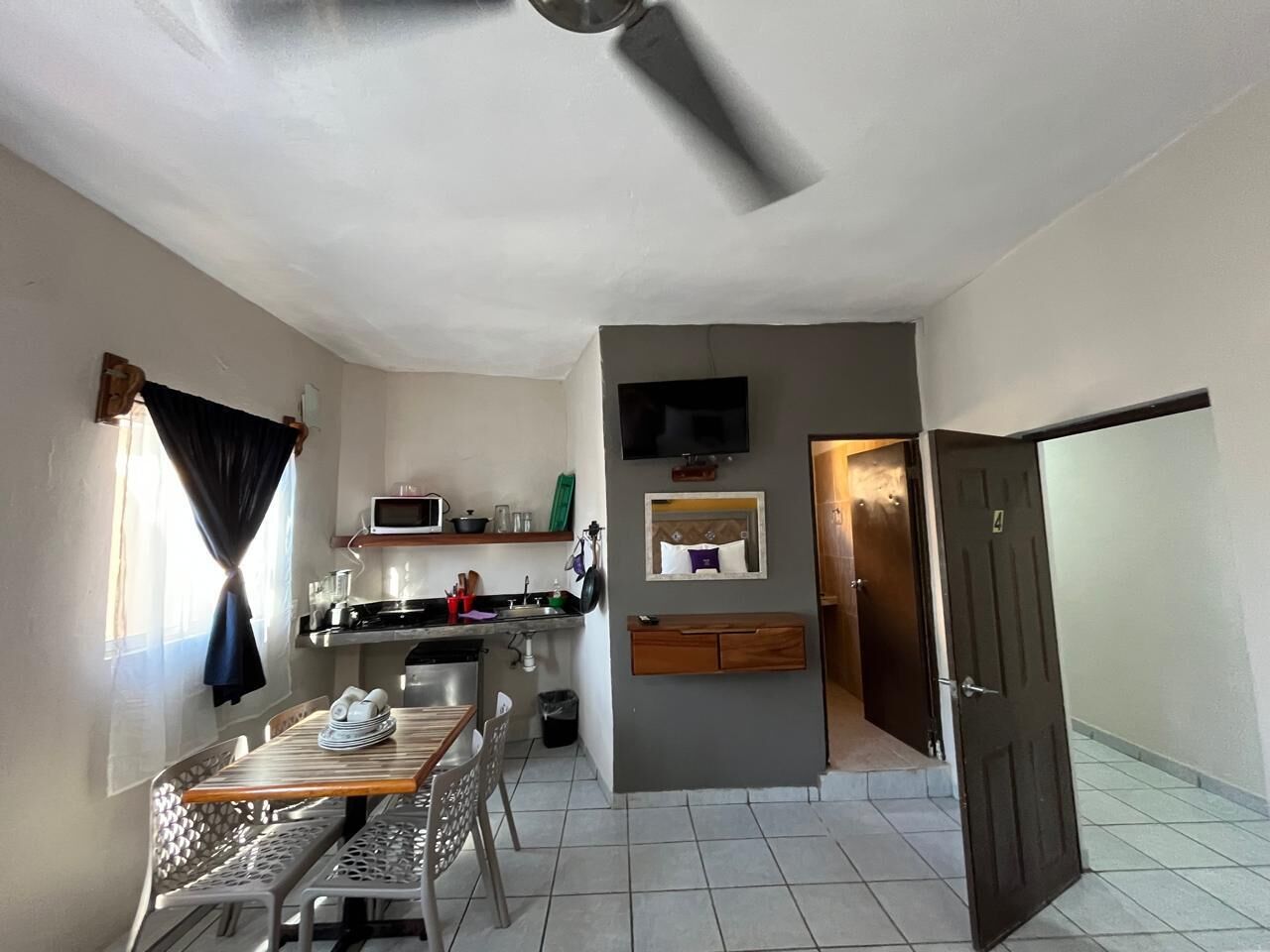 A compact kitchen with a microwave, sink, and dining area with a table and chairs.