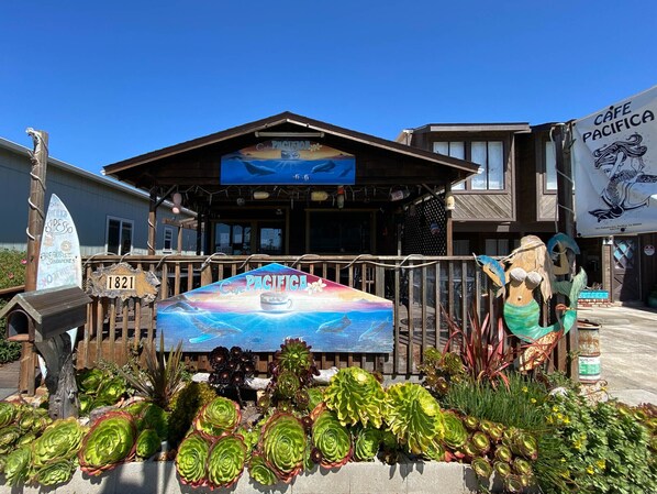 A café with a sign reading 'Café Pacifica,' featuring a beach scene with dolphins. - Beachfront Ocean Views 20 Mins to SF! (Pacifica)