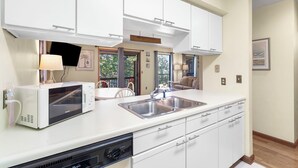 A modern kitchen with white cabinets, a built-in microwave, a sink, and a dishwasher.