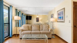 A living room with a beige sofa, a glass coffee table, and two floor lamps.