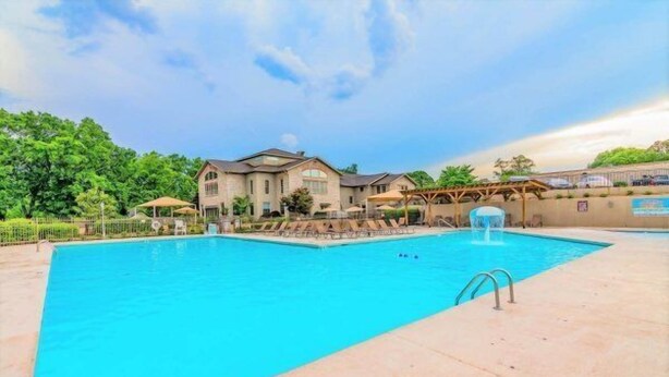 A rectangular swimming pool with a 4 FT depth marking, surrounded by a concrete deck and a wooden pergola structure.
