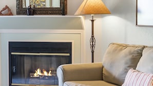 Una sala de estar con chimenea, un sofá, una lámpara y una mesita de centro.