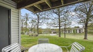 Une terrasse avec une table ronde et deux chaises, donnant sur un terrain de golf.