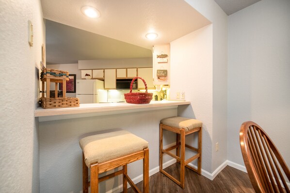 A kitchen with a white countertop, wooden stools, and a red basket. - 2 Bed, 2 Bath Walk-in Condo *Jetted Tub*Covered Patio* (Branson)