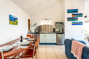 Una cucina moderna con zona pranzo, caratterizzata da un lavello in acciaio inossidabile, un forno a microonde e un tavolo imbandito con piatti e bicchieri da vino.