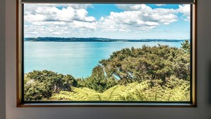 Une vue encadrée d’un paysage côtier, avec un ciel dégagé, une mer calme et une végétation luxuriante.