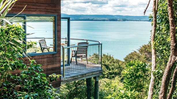 Une cabane en bois dotée d’un balcon donnant sur un lac.